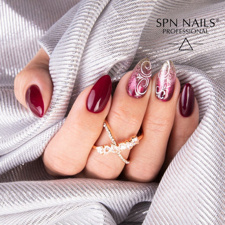 Manicured nails featuring SPN Nails UV/LED Gel Polish 777 Very Cherry Berry in deep red with intricate nail art. Perfect for elegant nail designs.