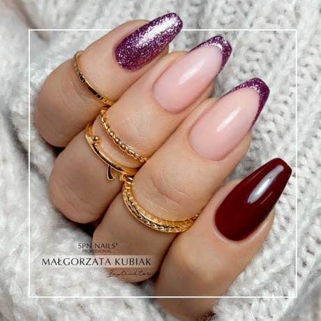 Manicured nails featuring SPN Nails UV/LED Gel Polish 811 Redberry Praline with glitter and solid red designs.