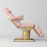 Manufakturo Aurélie beauty bed in Bare Blush with gold-finished base, side view with backrest raised and leg section lowered.
