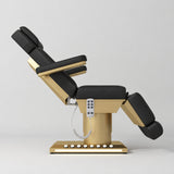 Manufakturo Aurélie beauty bed in Black with gold-finished base, side view with backrest raised and leg section lowered.