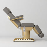 Manufakturo Aurélie beauty bed in Deep Ash with gold-finished base, side view with backrest raised and leg section lowered.