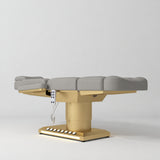 Manufakturo Aurélie beauty bed in Pearl Greige with gold-finished base, flat low-angle view.