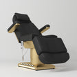 Manufakturo Aurélie beauty bed in Black with gold-finished base, reclined front three-quarter view.