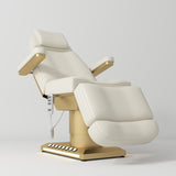 Manufakturo Aurélie beauty bed in Creamy with gold-finished base, reclined front three-quarter view.