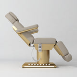 Manufakturo Aurélie beauty bed in Stone Taupe with gold-finished base, side view with backrest raised and leg section lowered.