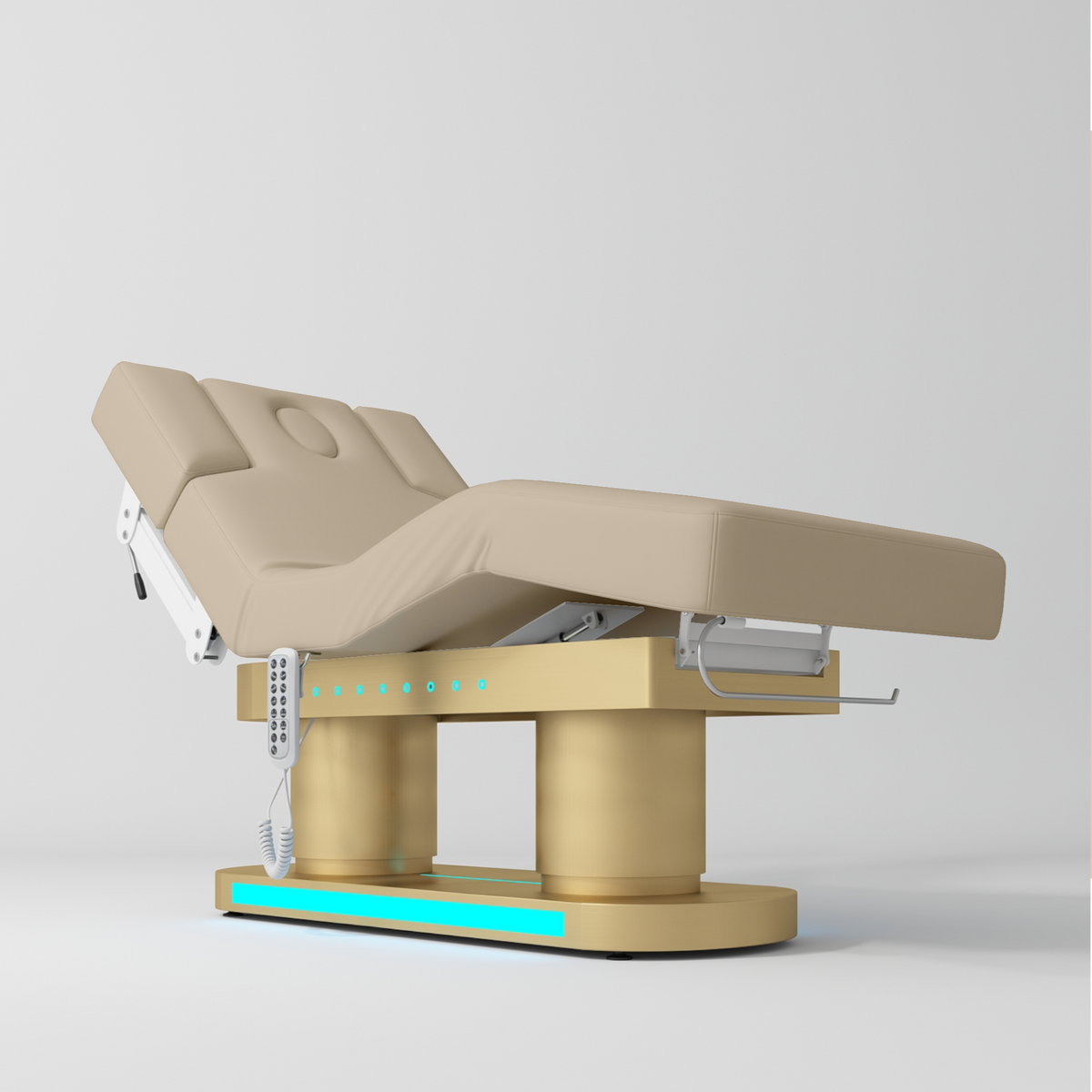An adjustable electric treatment bed with a beige padded frame and base, featuring a control panel and white support arms, shown on a light gray studio background.