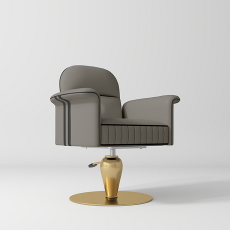 A modern gray upholstered salon chair with dark piping, a ribbed seat, and a polished gold pedestal base on a light gray studio background.