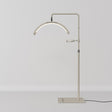 A modern floor lamp with a slim, adjustable metal stand, a curved light bar, and a flat rectangular base, shown against a neutral light gray background.
