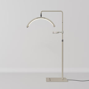 A modern floor lamp with a slim, adjustable metal stand, a curved light bar, and a flat rectangular base, shown against a neutral light gray background.