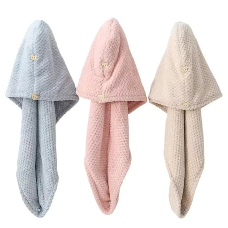 Set of three microfiber hair towels in pastel blue, pink, and beige with button closures, ideal for drying high porosity hair.