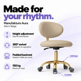 Manufakturo Aura Warm Beige beauty stool with gas-lift height adjustment, 360-degree swivel, padded backrest, gold five-spoke base, five castors and 150 kg maximum load.