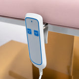 Manufakturo Chérie Bare Blush electric massage bed — close-up of the two-button hand-held height control and upholstery.