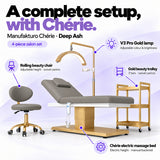 Manufakturo Chérie Deep Ash salon set features: electric bed height and manual backrest adjustment, height-adjustable rolling chair, V3 Pro Gold lamp with adjustable colour and brightness, and three-tier gold trolley.