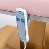 Manufakturo Chérie Light Pink electric massage bed — close-up of the two-button hand-held height control and upholstery.