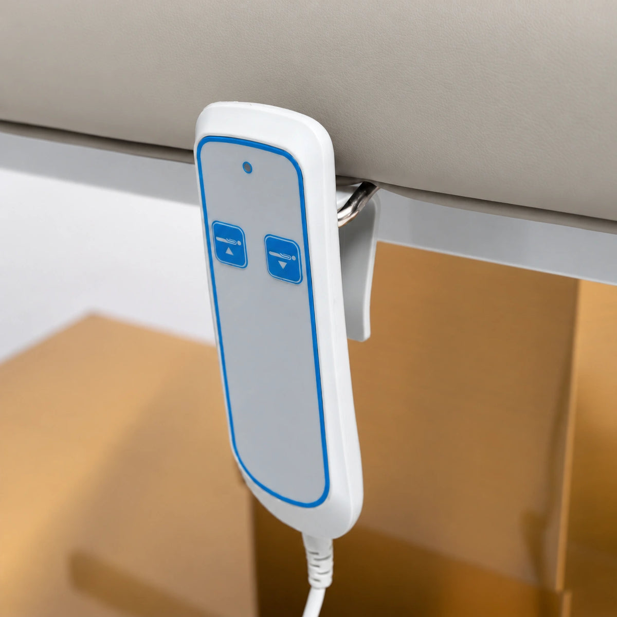 Manufakturo Chérie Pearl Greige electric massage bed — close-up of the two-button hand-held height control and upholstery.