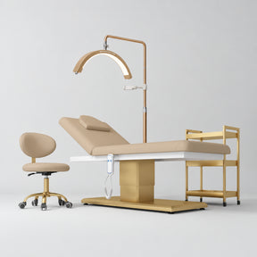 Manufakturo Chérie Warm Beige four-piece salon set with electric massage bed, matching rolling beauty chair, V3 Pro Gold treatment lamp and empty three-tier gold trolley.