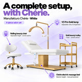 Manufakturo Chérie White salon set features: electric bed height and manual backrest adjustment, height-adjustable rolling chair, V3 Pro Gold lamp with adjustable colour and brightness, and three-tier gold trolley.