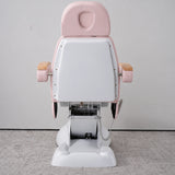 Rear view of the Manufakturo Grace Bare Blush electric beauty bed, showing the upholstered headrest, white rigid rear cover and adjustment mechanism.