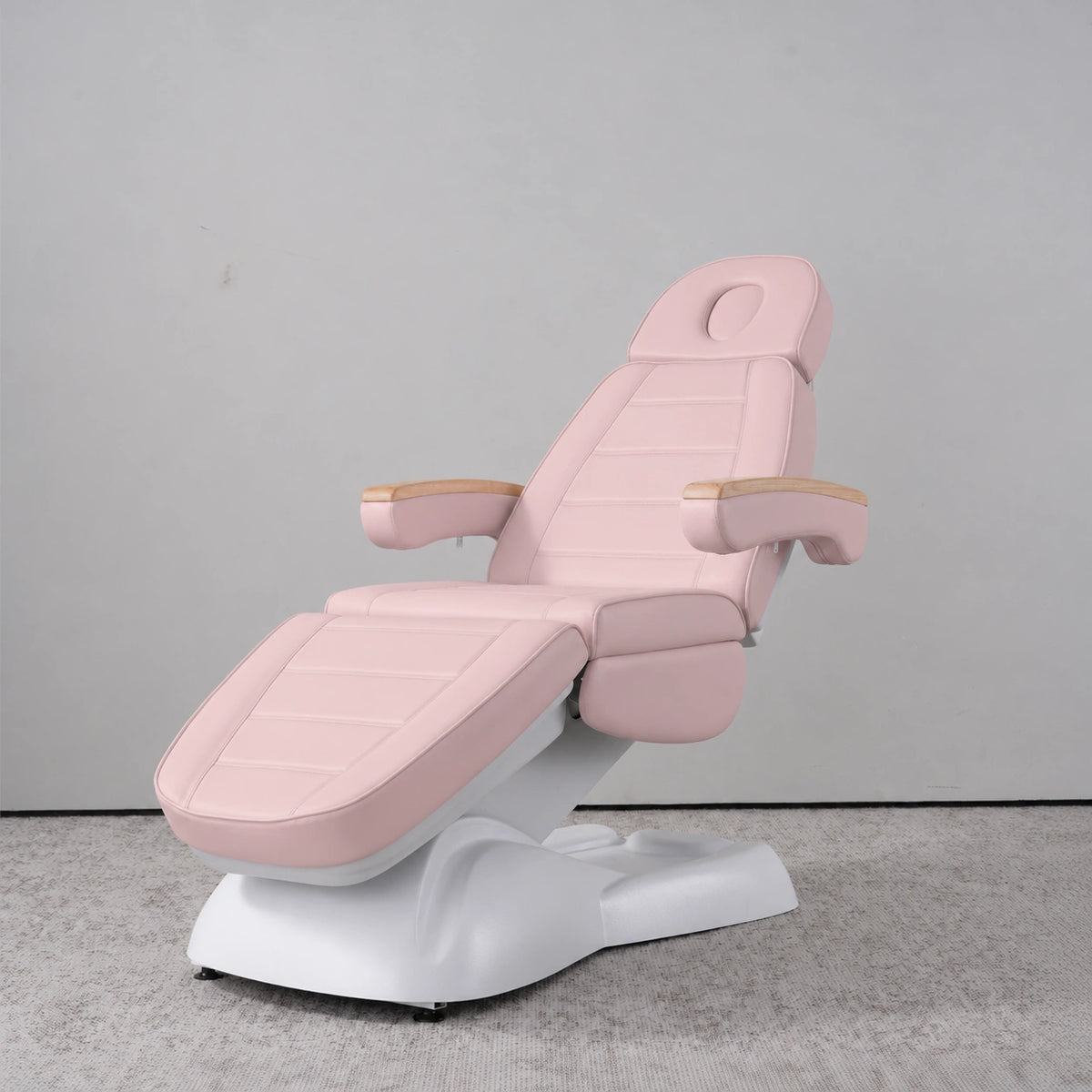 Manufakturo Grace Bare Blush electric beauty bed in a treatment position, with wooden armrest caps and a white sculpted base.
