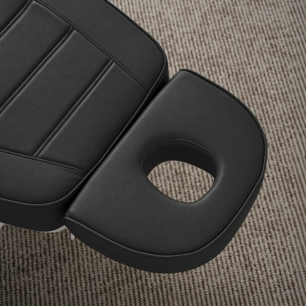 Manufakturo Grace Black electric beauty bed headrest detail, showing the open massage face hole and matching stitched upholstery.