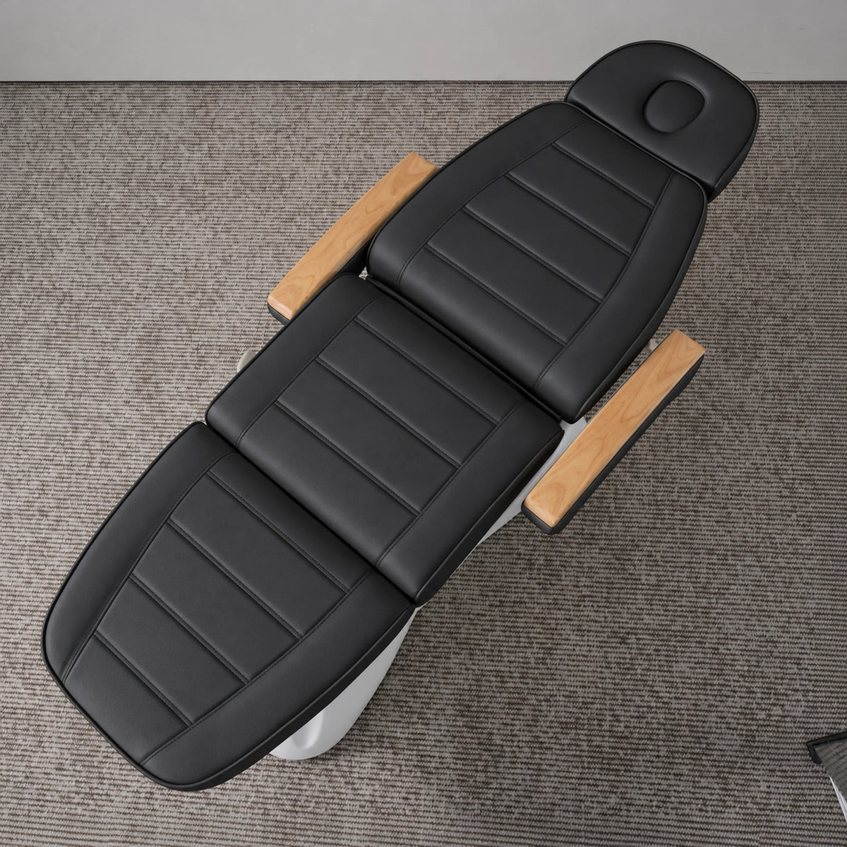 Manufakturo Grace Black electric beauty bed viewed from above, showing the segmented upholstery, face insert and wooden armrest caps.