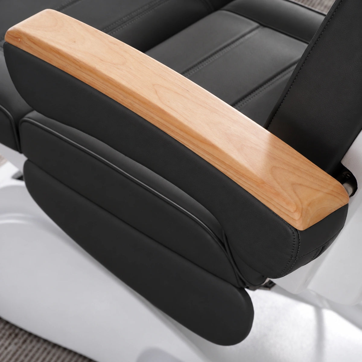 Manufakturo Grace Black electric beauty bed armrest detail, showing the natural wooden top and matching upholstered side cushions.