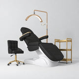 Manufakturo Grace Black complete salon set with electric beauty bed, Noblesse chair, V3 Pro Gold treatment lamp and three-tier gold trolley.
