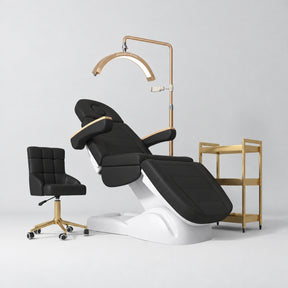 Manufakturo Grace Black complete salon set with electric beauty bed, Noblesse chair, V3 Pro Gold treatment lamp and three-tier gold trolley.