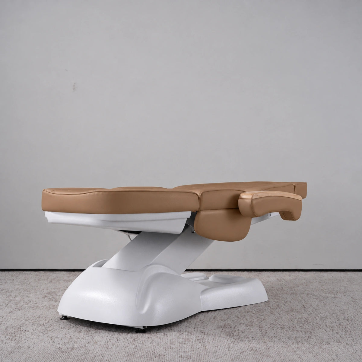 Manufakturo Grace Caramel electric beauty bed lying flat, with wooden armrest caps and the original white inclined lift and sculpted base.
