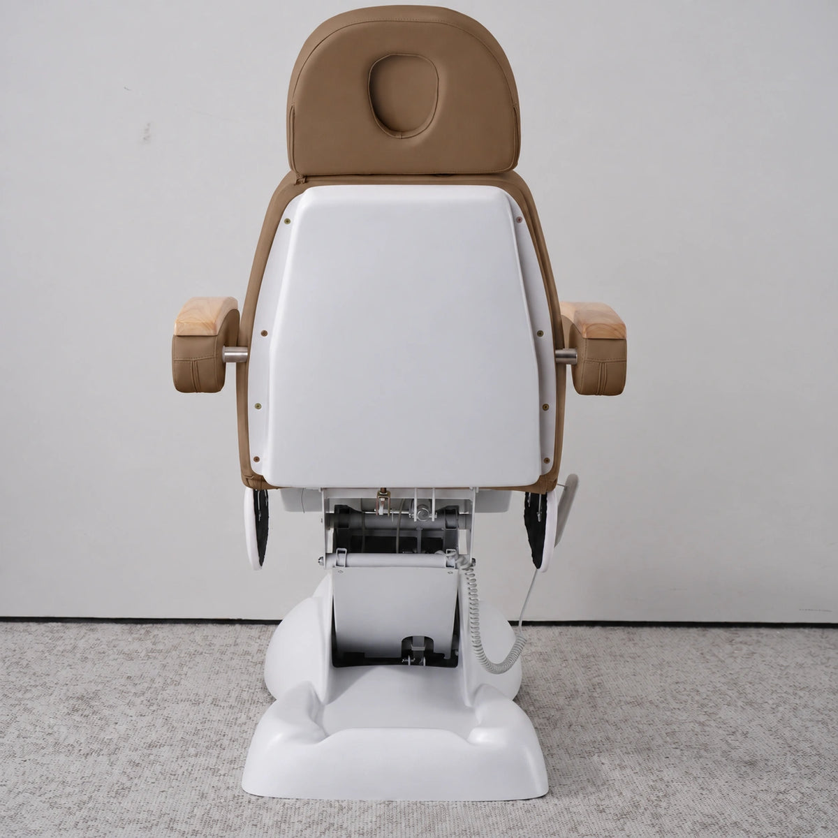 Rear view of the Manufakturo Grace Caramel electric beauty bed, showing the upholstered headrest, white rigid rear cover and adjustment mechanism.