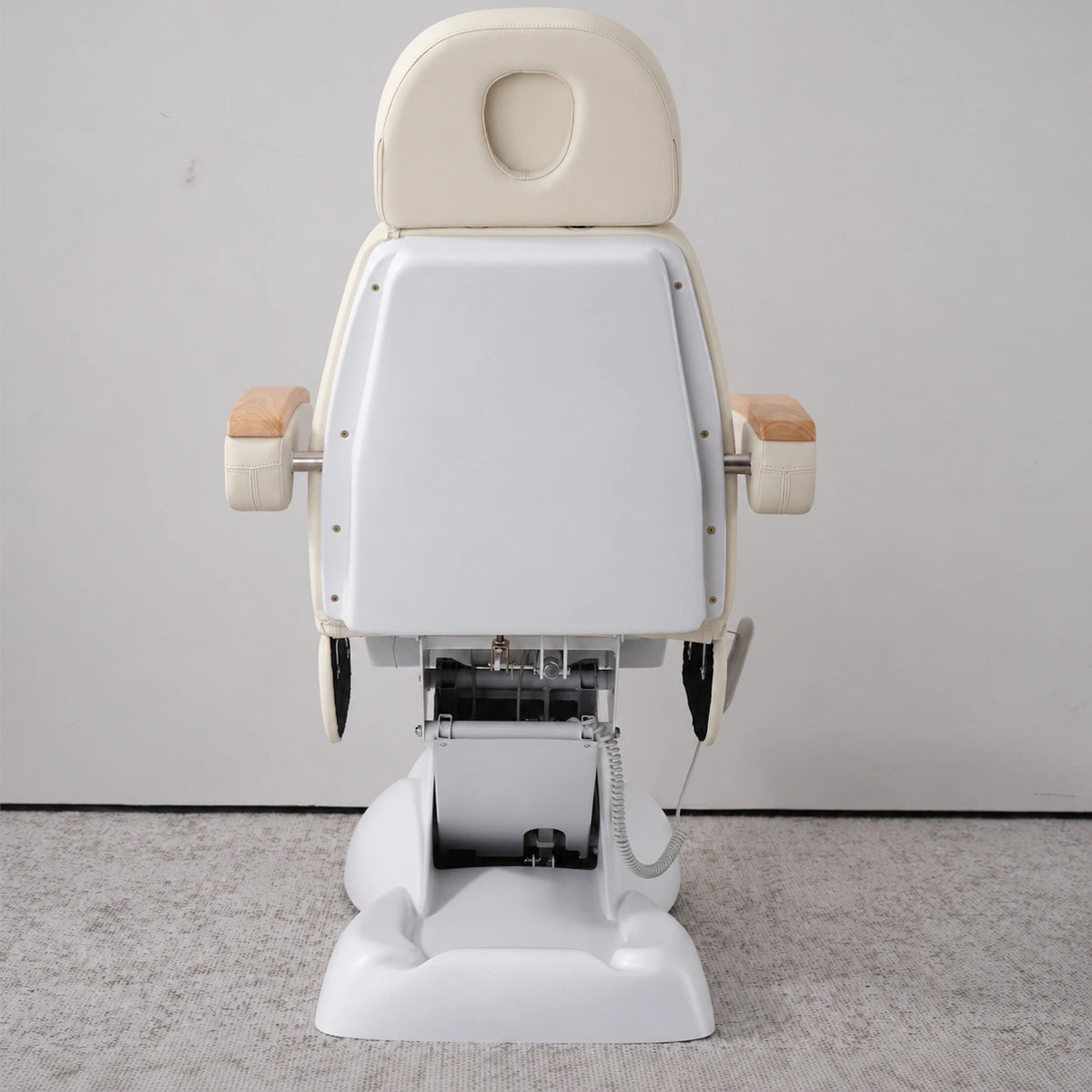 Rear view of the Manufakturo Grace Creamy electric beauty bed, showing the upholstered headrest, white rigid rear cover and adjustment mechanism.
