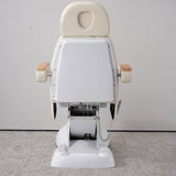 Rear view of the Manufakturo Grace Creamy electric beauty bed, showing the upholstered headrest, white rigid rear cover and adjustment mechanism.