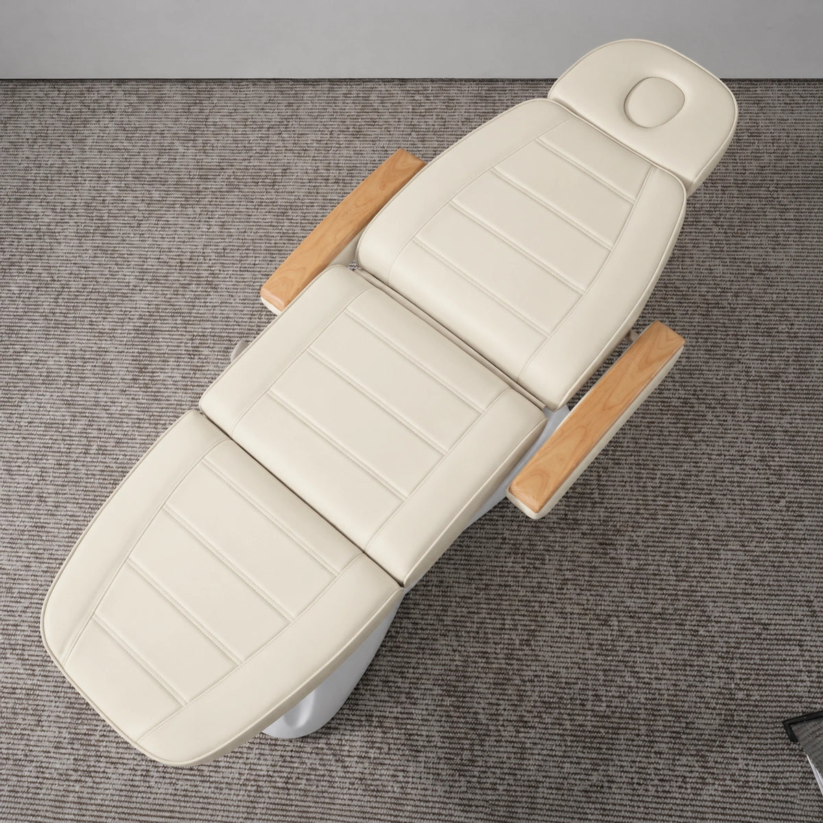 Manufakturo Grace Creamy electric beauty bed viewed from above, showing the segmented upholstery, face insert and wooden armrest caps.