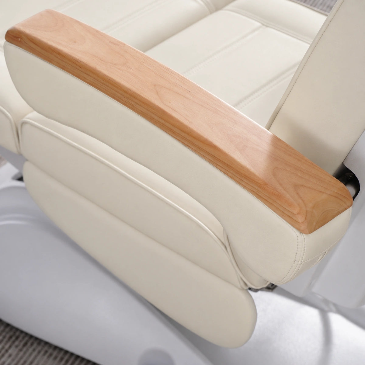 Manufakturo Grace Creamy electric beauty bed armrest detail, showing the natural wooden top and matching upholstered side cushions.