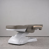 Manufakturo Grace Deep Ash electric beauty bed lying flat, with wooden armrest caps and the original white inclined lift and sculpted base.