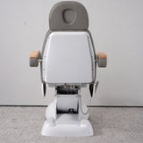 Rear view of the Manufakturo Grace Deep Ash electric beauty bed, showing the upholstered headrest, white rigid rear cover and adjustment mechanism.