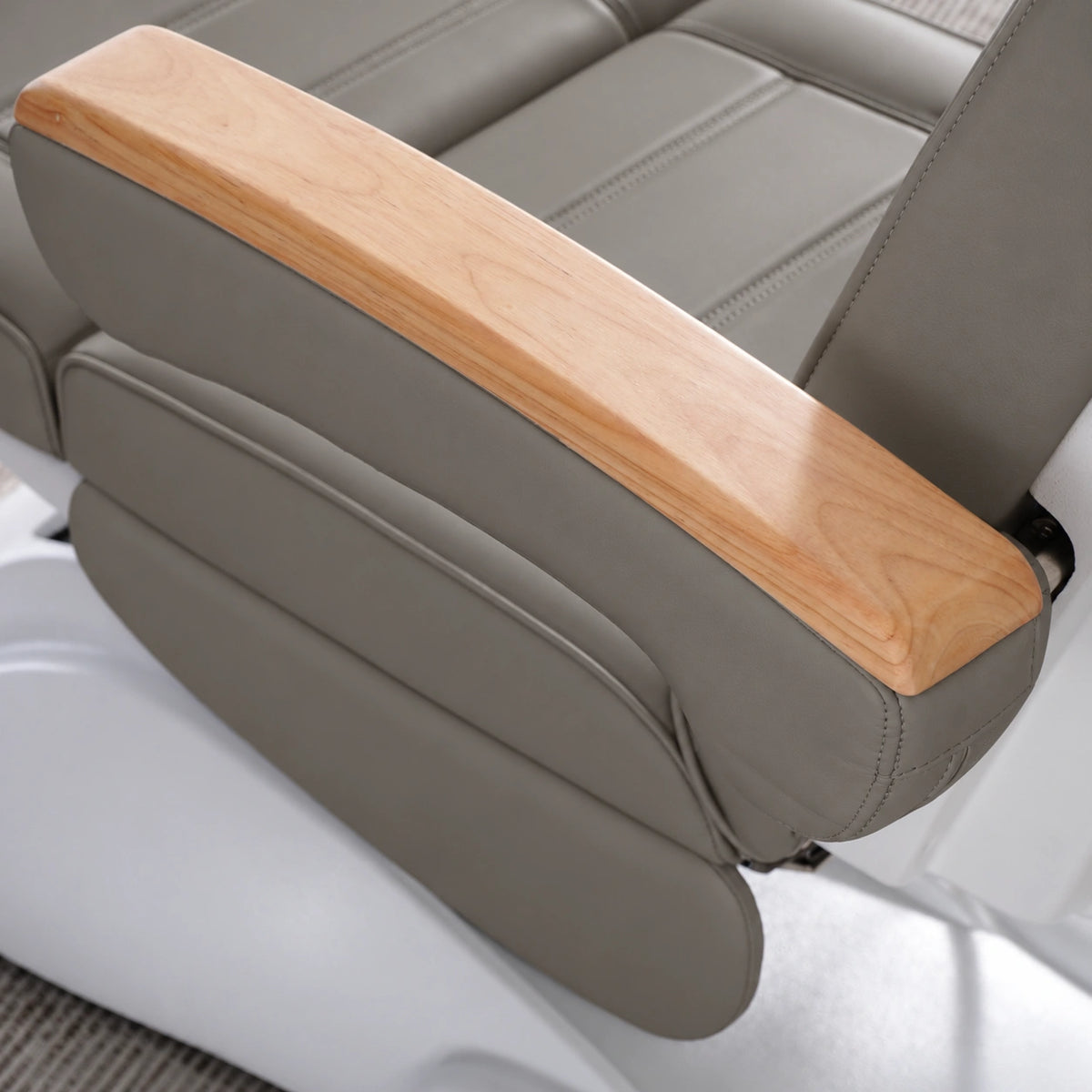 Manufakturo Grace Deep Ash electric beauty bed armrest detail, showing the natural wooden top and matching upholstered side cushions.