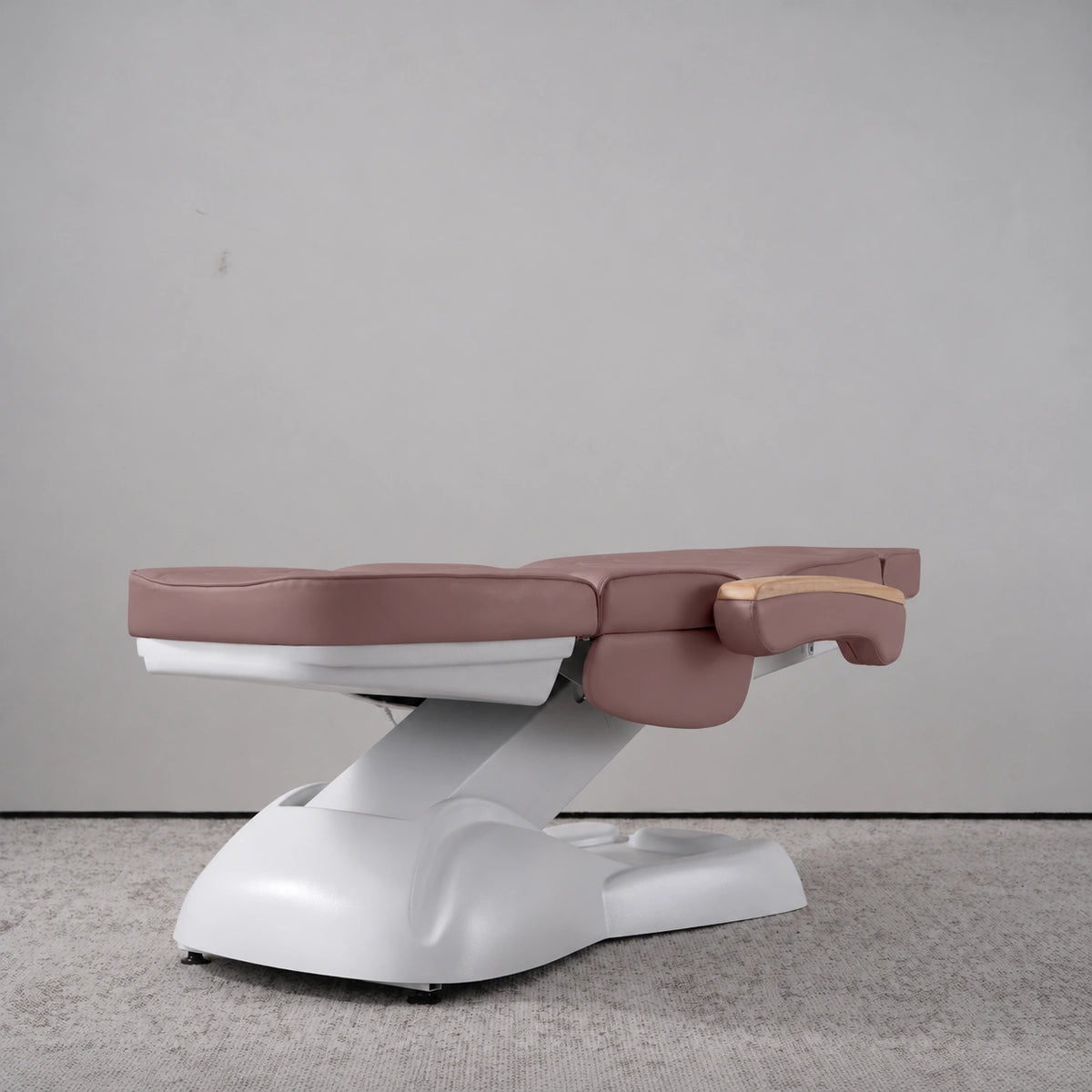Manufakturo Grace Dusty Rose electric beauty bed lying flat, with wooden armrest caps and the original white inclined lift and sculpted base.