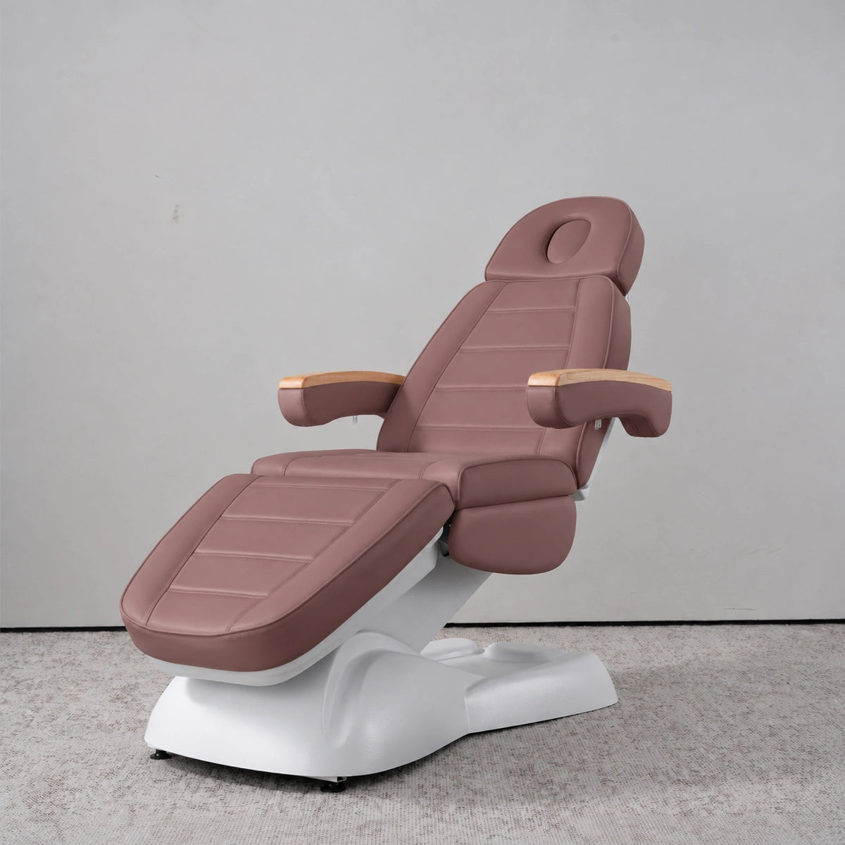 Manufakturo Grace Dusty Rose electric beauty bed in a treatment position, with wooden armrest caps and a white sculpted base.