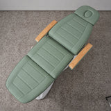 Manufakturo Grace Olive electric beauty bed viewed from above, showing the segmented upholstery, face insert and wooden armrest caps.