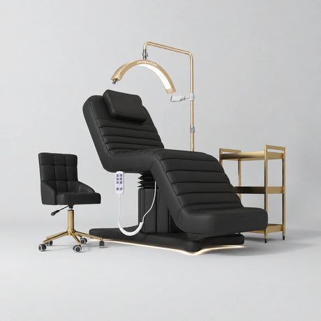 Manufakturo Grandeur Black complete studio set with beauty bed, Noblesse chair, gold trolley and V3 Pro Gold treatment lamp, photographed against the original grey studio background.