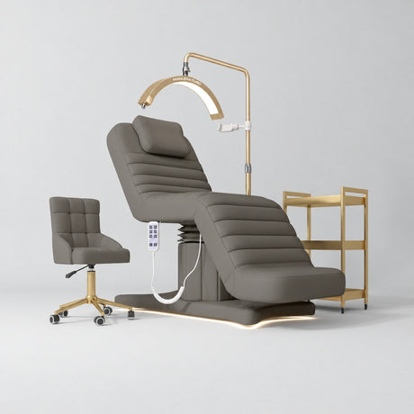 Manufakturo Grandeur Deep Ash complete studio set with beauty bed, Noblesse chair, gold trolley and V3 Pro Gold treatment lamp, photographed against the original grey studio background.