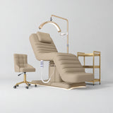 Manufakturo Grandeur Warm Beige complete studio set with beauty bed, Noblesse chair, gold trolley and V3 Pro Gold treatment lamp, photographed against the original grey studio background.