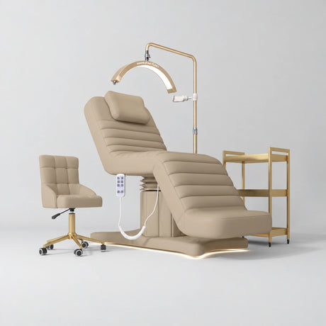 Manufakturo Grandeur Warm Beige complete studio set with beauty bed, Noblesse chair, gold trolley and V3 Pro Gold treatment lamp, photographed against the original grey studio background.