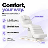 Manufakturo Grandeur White electric beauty bed with 3 motors for height, backrest and leg rest adjustment, hand-held control, LED base lighting and 300 kg maximum load.