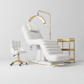 Manufakturo Grandeur White complete studio set with beauty bed, Noblesse chair, gold trolley and V3 Pro Gold treatment lamp, photographed against the original grey studio background.