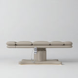 Manufakturo Imperial Signature Stone Taupe heated beauty bed fully flat in side view, showing smooth segmented upholstery, hand-held control and illuminated matching base.