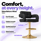 Manufakturo Mirae Black salon and reception bar stool with lever-operated gas-lift height adjustment, padded curved armrests, a panelled backrest, cushioned seat, integrated metal footrest and gold-finished pedestal base.