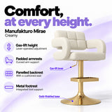 Manufakturo Mirae Creamy salon and reception bar stool with lever-operated gas-lift height adjustment, padded curved armrests, a panelled backrest, cushioned seat, integrated metal footrest and gold-finished pedestal base.
