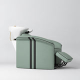 Manufakturo Monaco Olive backwash unit with white basin and extended electric leg rest, shown from a low side angle.